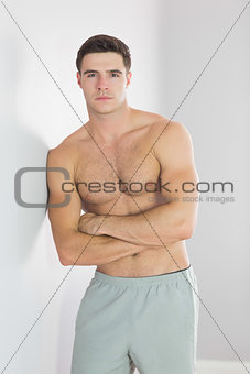 Serious handsome man leaning topless against wall
