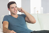 Cheerful handsome man relaxing on couch phoning