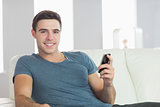 Cheerful handsome man relaxing on couch texting