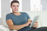 Smiling handsome man relaxing on couch using tablet