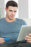 Content handsome man relaxing on couch using tablet shopping online