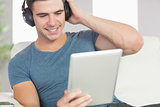 Happy handsome man using tablet listening to music
