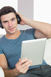 Smiling handsome man using tablet listening to music