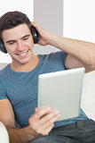 Content handsome man using tablet listening to music