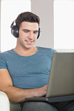 Content handsome man using laptop listening to music