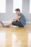 Focused handsome man using laptop sitting on floor
