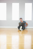 Happy handsome man leaning against wall using laptop