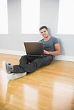 Content handsome man leaning against wall using laptop