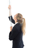 Attractive blonde businesswoman climbing a silver chain