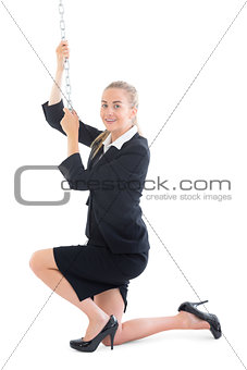Content young businesswoman kneeling on floor pulling a chain