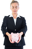 Serious chic businesswoman presenting a piggy bank
