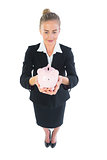 High angle view of modern businesswoman showing a piggy bank