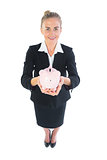 High angle view of attractive businesswoman holding a piggy bank