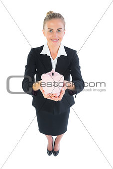 High angle view of attractive businesswoman holding a piggy bank