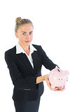 Attractive chic businesswoman presenting a piggy bank