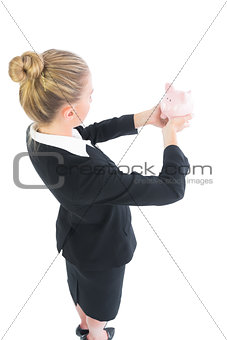 Side view of blonde businesswoman holding a piggy bank