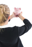 Blonde businesswoman showing a piggy bank