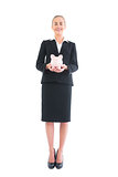 Cheerful young businesswoman presenting pink piggy bank