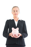 Serious young businesswoman holding pink piggy bank