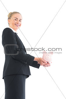 Attractive young businesswoman holding pink piggy bank
