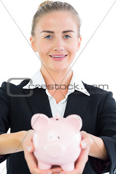 Pretty businesswoman holding pink piggy bank