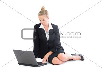 Beautiful young businesswoman sitting on floor using her notebook