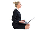 Side view of content pretty businesswoman sitting on floor using her notebook
