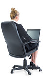 Rear view of blonde young businesswoman sitting on an office chair using her laptop