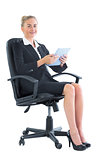 Lovely young businesswoman sitting on an office chair holding her tablet