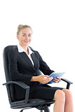 Attractive well dressed businesswoman sitting on an office chair holding a tablet