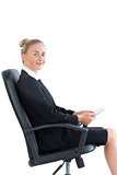 Gorgeous young businesswoman sitting on an office chair holding her tablet