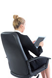 Young businesswoman sitting on her office chair holding a tablet