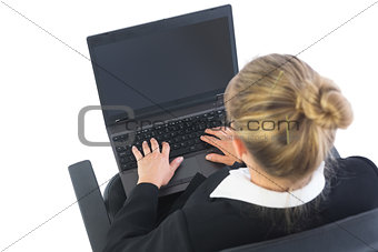 Rear view of businesswoman sitting in swivel chair using laptop