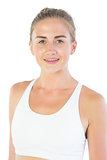 Attractive smiling blonde wearing sports bra looking at camera