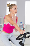 Sporty stern blonde training on exercise bike listening to music