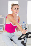 Sporty content blonde training on exercise bike listening to music