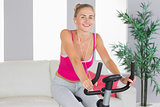 Sporty laughing blonde training on exercise bike