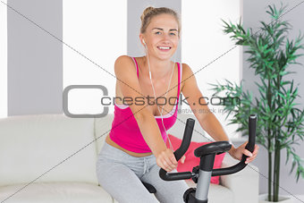 Sporty laughing blonde training on exercise bike