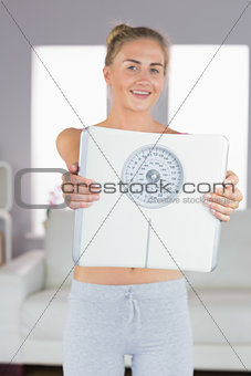 Sporty cheerful blonde holding scales