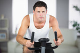 Attractive sporty man exercising on bike looking at camera