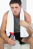 Sporty exhausted man holding water bottle