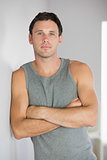 Sporty attractive man leaning against wall with arms crossed