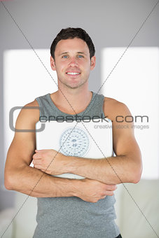 Sporty cheerful man holding a scale