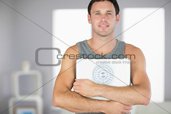 Sporty smiling man holding a scale