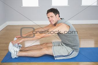 Smiling sporty man stretching his legs