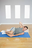 Attractive sporty man doing abdominal crunch looking at camera