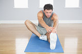 Attractive sporty man stretching his right leg