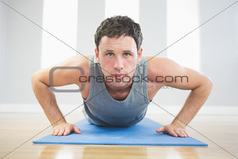 Handsome sporty man doing push ups on blue mat
