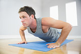 Attractive sporty man doing push ups on blue mat