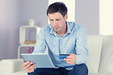 Content casual man using tablet and credit card